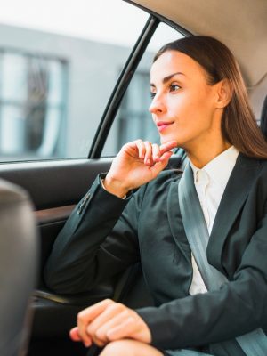 businesswoman-looking-through-window-while-traveling-by-car