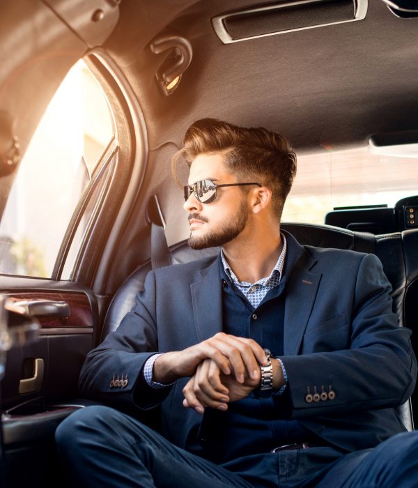 Businessman with shades in limousine, looking trough the window